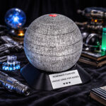 Round cremation urn with textured sci-fi design and red heart detail, displayed among futuristic decorative elements.