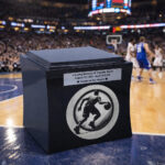 Black cremation urn with basketball player engraving and memorial plaque on basketball court