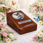 Wooden cremation urn with butterfly artwork, surrounded by blooming flowers and colorful butterflies.