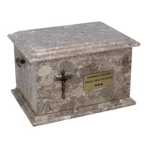 Urna z kamienia z tabliczką pamiątkową i krzyżem katolickim
