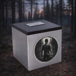Stainless steel cremation urn with wooden lid and engraved woodcutter design, set in a forest environment.