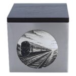 Nahaufnahme der Edelstahlurne mit Zuggravur und dunklem Holzdeckel.