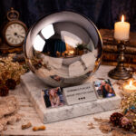 Modern cremation urn sphere with photo holders displayed in a warm home memorial setting with candles.