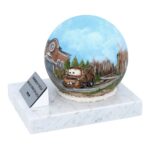 Ujęcie pod kątem na ręcznie malowaną kulę urny ze stali nierdzewnej spoczywającą na marmurowej podstawie