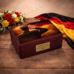 German patriotic urn on rustic wooden table with flowers and national flag backdrop