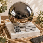 Adult memorial urn with QR code displayed with white flowers, soft fabric and a smartphone in a peaceful setting.