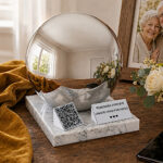 Companion memorial urn with QR code displayed beside flowers, a smartphone and a framed photograph of an elderly couple.
